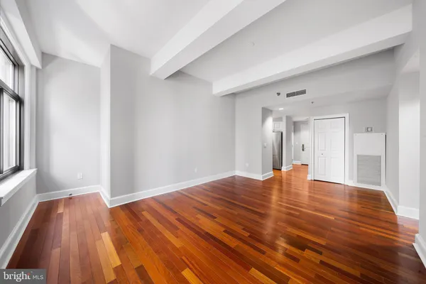 a view of empty room with wooden floor and fan