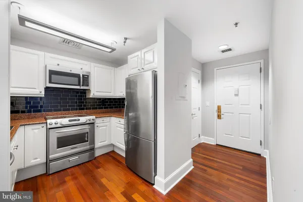 a kitchen with granite countertop a refrigerator and a stove top oven