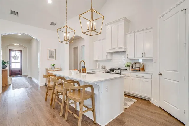 a kitchen with stainless steel appliances granite countertop a stove a refrigerator a sink dishwasher a dining table and chairs with wooden floor