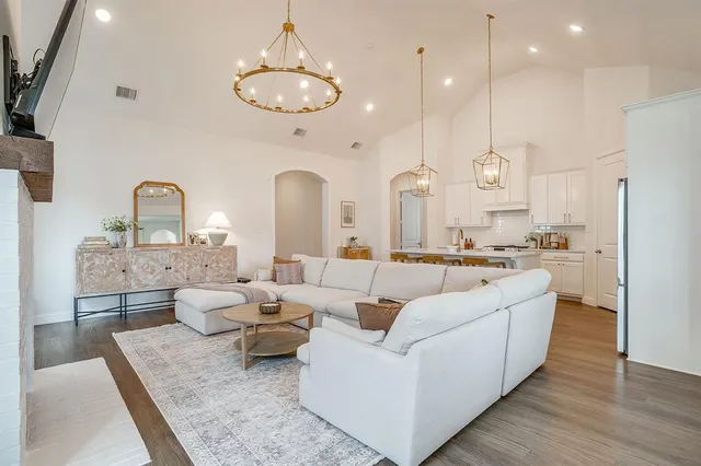 a living room with furniture kitchen view and a chandelier