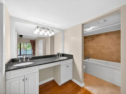 a bathroom with a granite countertop sink a toilet a mirror and shower