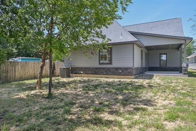 2936 Henry Road Lancaster, TX 75134 - Photo 26 of 28 Exterior featuring a covered patio, stacked stone facade accents, light-colored siding, and a fenced perimeter