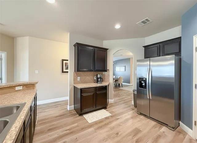 a kitchen with granite countertop a refrigerator and a stove top oven