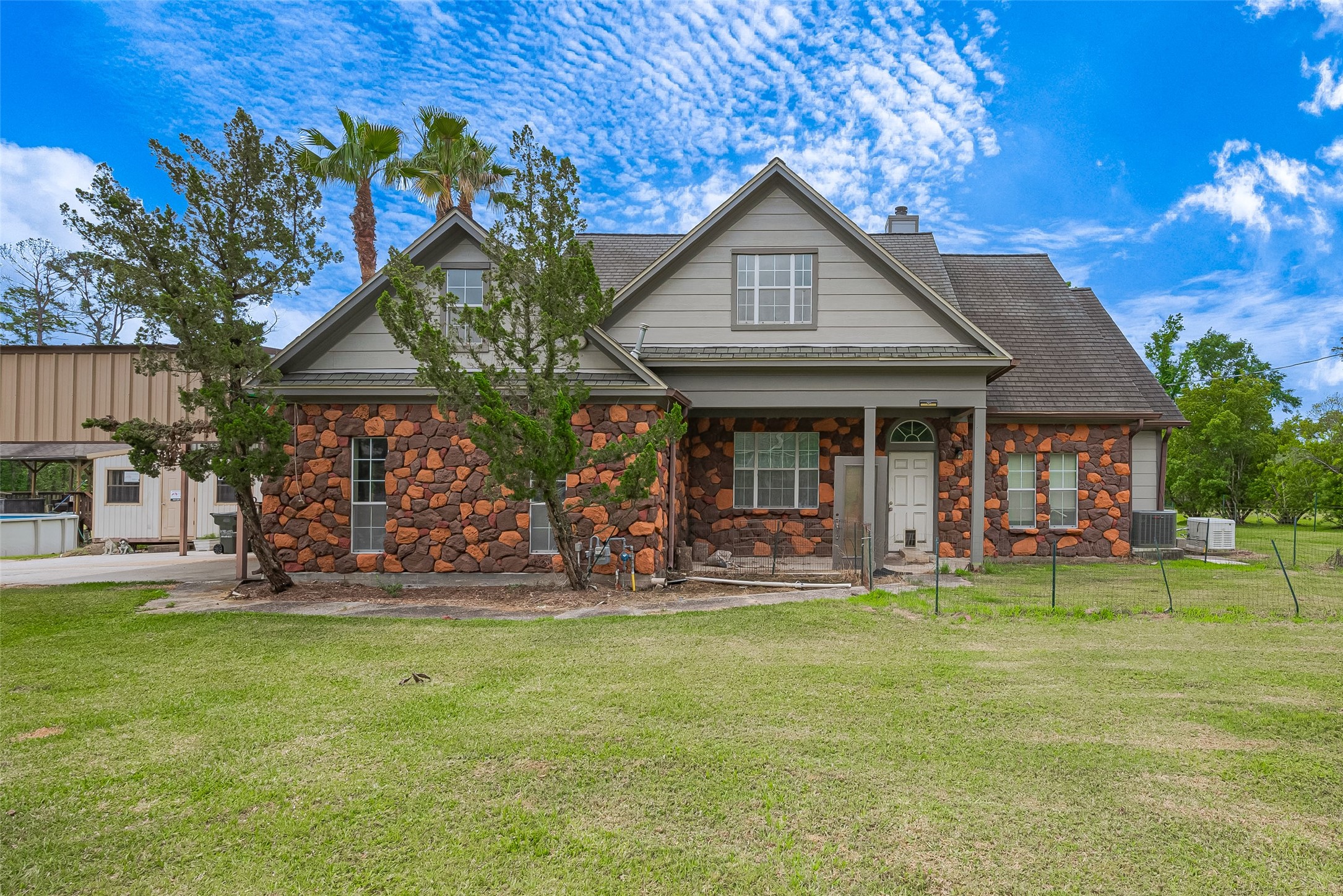 2499 Southline Road Conroe, TX 77384 - Photo 3 of 49 Charming country-style home featuring a distinctive stone exterior, welcoming covered front porch, and spacious yard.
