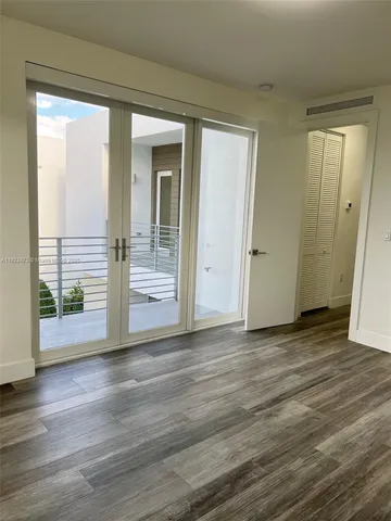 a view of a hallway with wooden floor and glass door