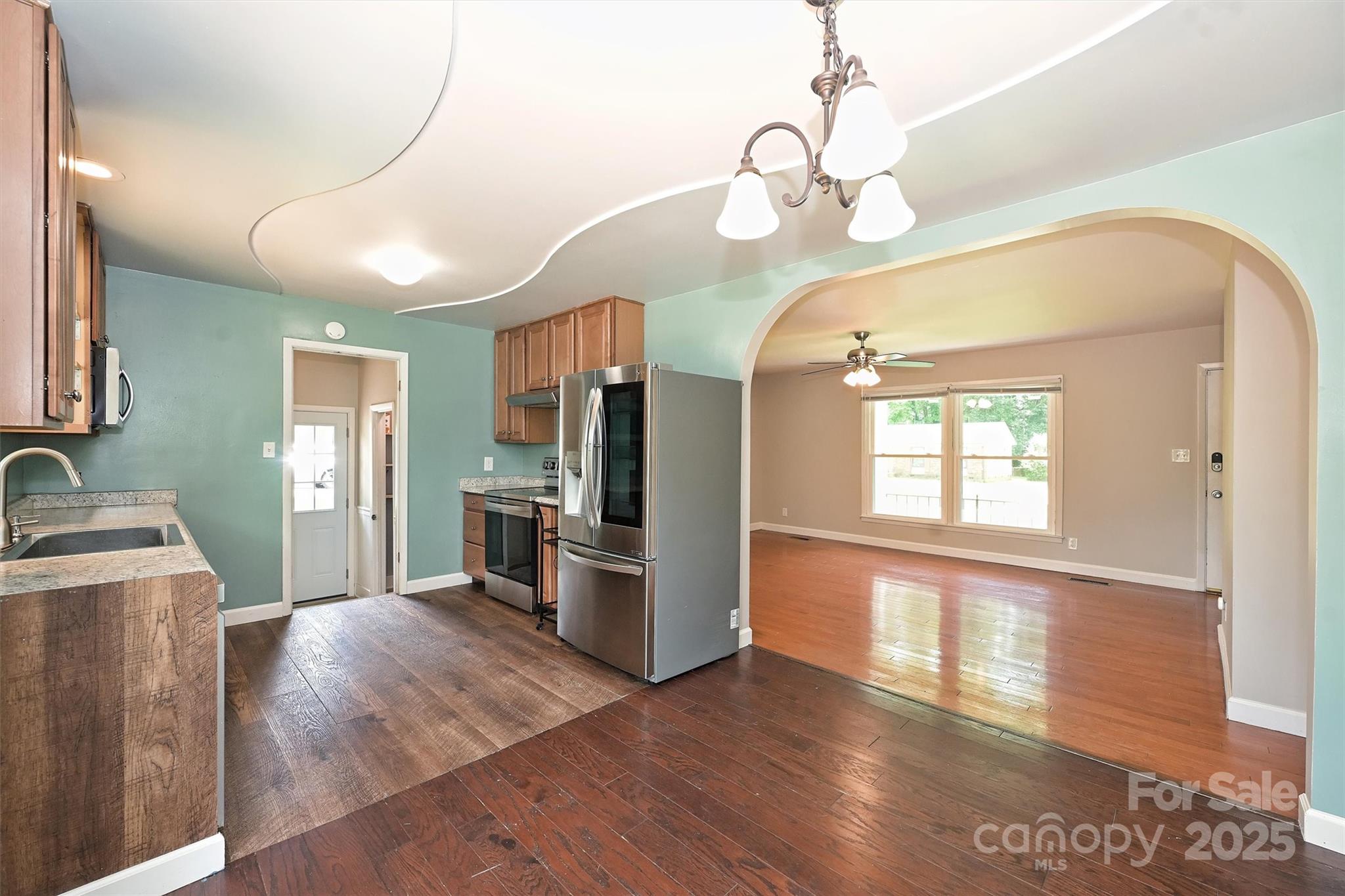 3729 Woodleaf Road Charlotte, NC 28205 - Photo 6 of 23 a view of a kitchen with a sink wooden floor and a living room