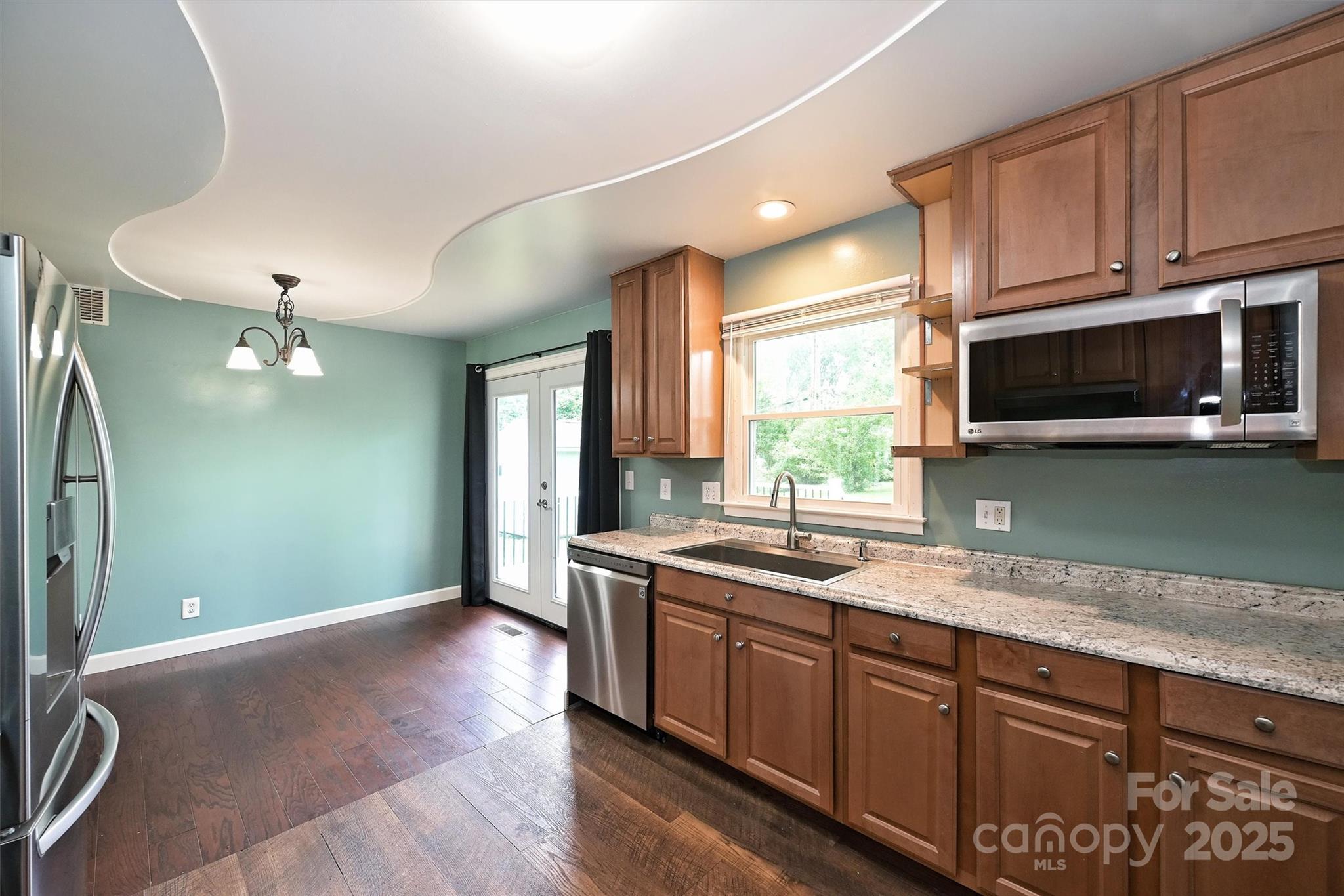 3729 Woodleaf Road Charlotte, NC 28205 - Photo 8 of 23 a kitchen with stainless steel appliances granite countertop a sink a stove top oven and wooden floor