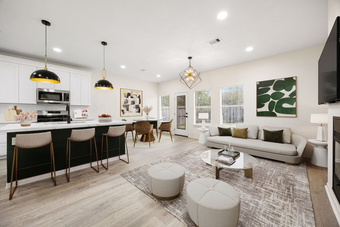 An inviting open-concept living area filled with natural light, featuring a modern kitchen with a large island, stylish pendant lighting, and seamless flow into the dining and family room—perfect for everyday living and entertaining.