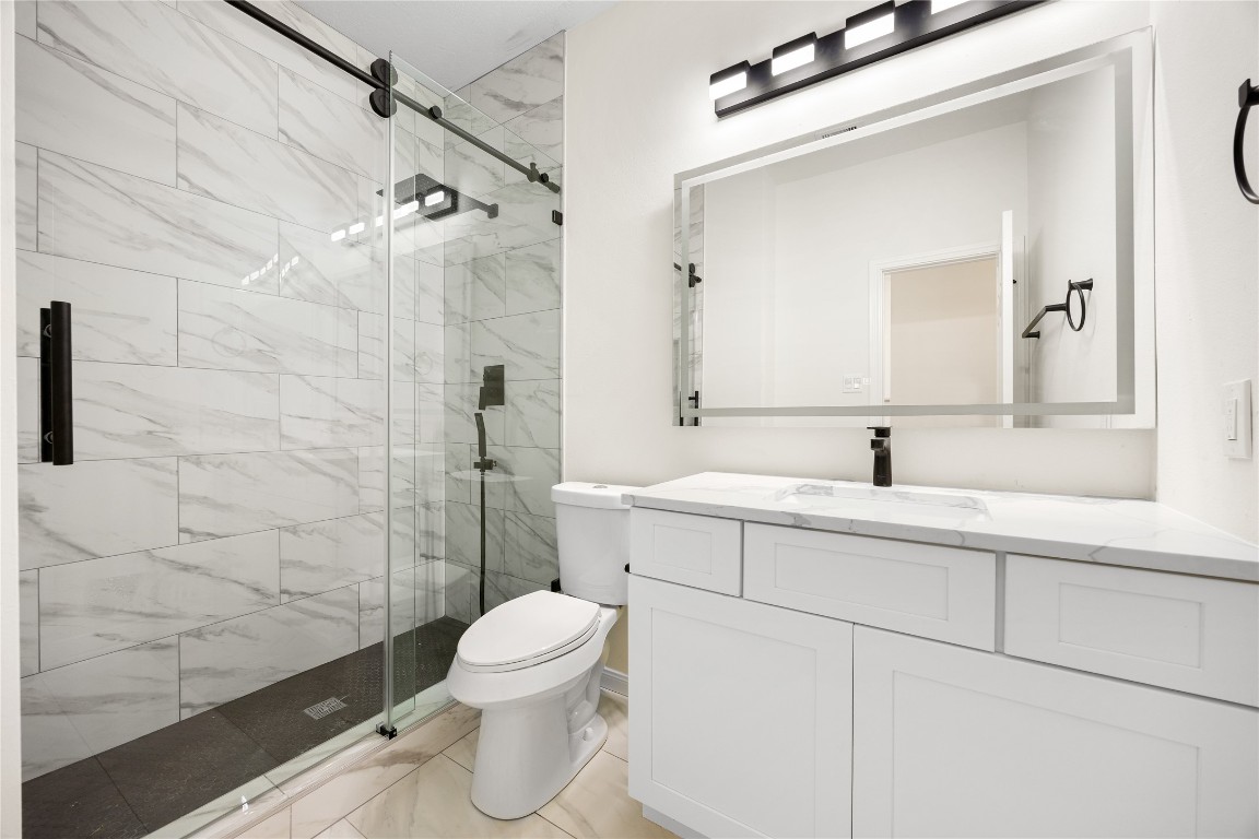 13735 Sablegarden Lane Houston, TX 77014 - Photo 16 of 20 Beautifully updated bathroom featuring a sleek walk-in shower with frameless glass doors and modern matte-black fixtures. The spacious vanity offers ample storage and a clean, contemporary look, complemented by bright lighting and marble-style tile throughout. A fresh, elegant space designed for comfort and everyday convenience.