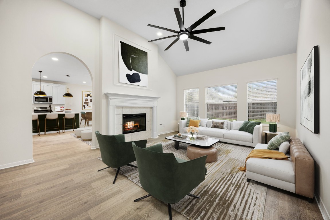 13735 Sablegarden Lane Houston, TX 77014 - Photo 9 of 20 Beautifully designed living room featuring soaring ceilings, a striking fireplace, and a wall of windows that fills the space with natural light. The open layout seamlessly connects to the kitchen, creating a warm and inviting atmosphere perfect for gatherings, everyday living, and effortless entertaining