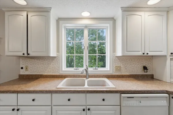a kitchen with granite countertop white cabinets and window