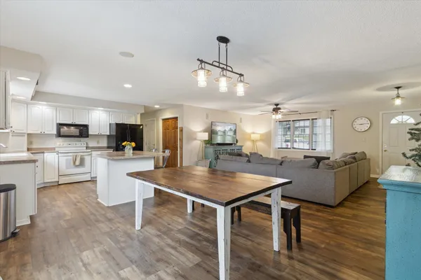 a living room with couches chairs and kitchen view with wooden floor