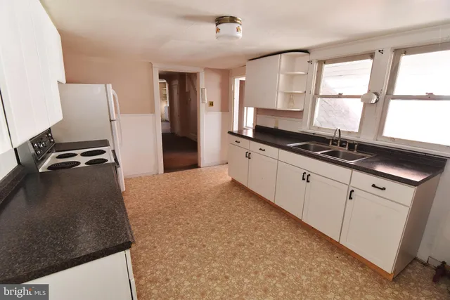 a kitchen with granite countertop a stove a sink and a refrigerator