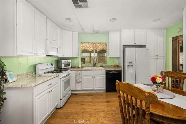 a kitchen with a refrigerator a stove a sink dishwasher with a dining table and chairs