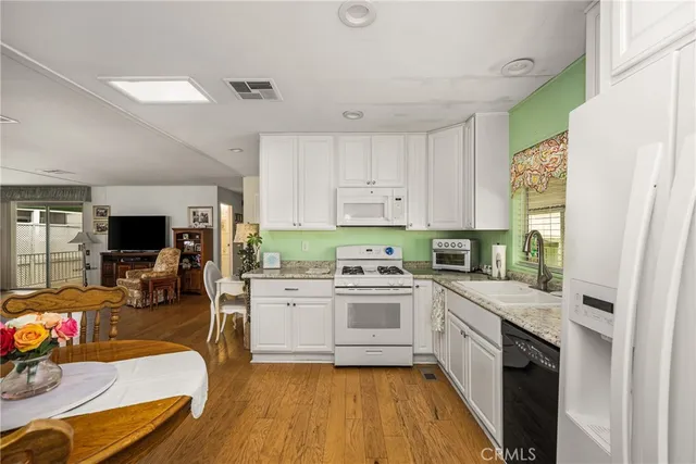 a kitchen with a stove a sink dishwasher a refrigerator and a dining table with wooden floor