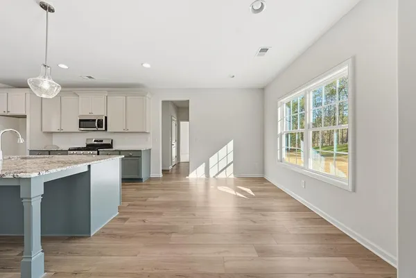 a kitchen with granite countertop a stove a sink dishwasher a refrigerator and white cabinets with wooden floor