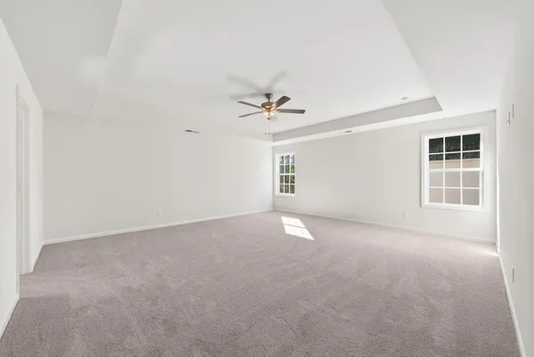 an empty room with windows and ceiling fan