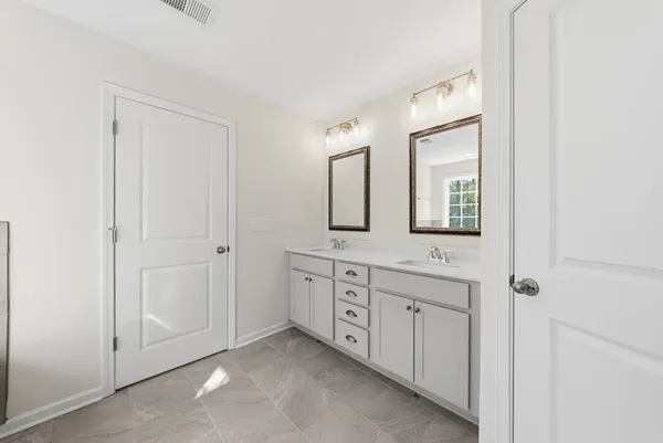a spacious bathroom with 2 sink and a mirror