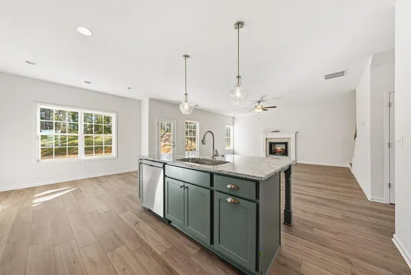 a kitchen with stainless steel appliances granite countertop a sink a stove and a wooden floor