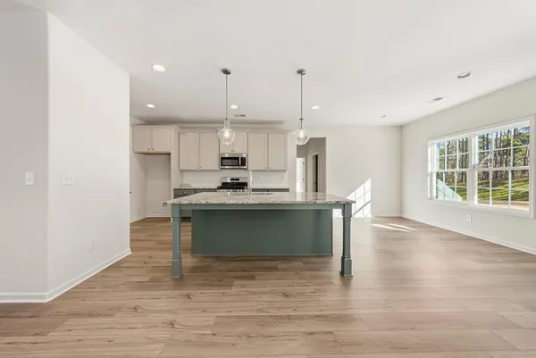 a kitchen with stainless steel appliances kitchen island wooden cabinets a stove a sink and a wooden floors