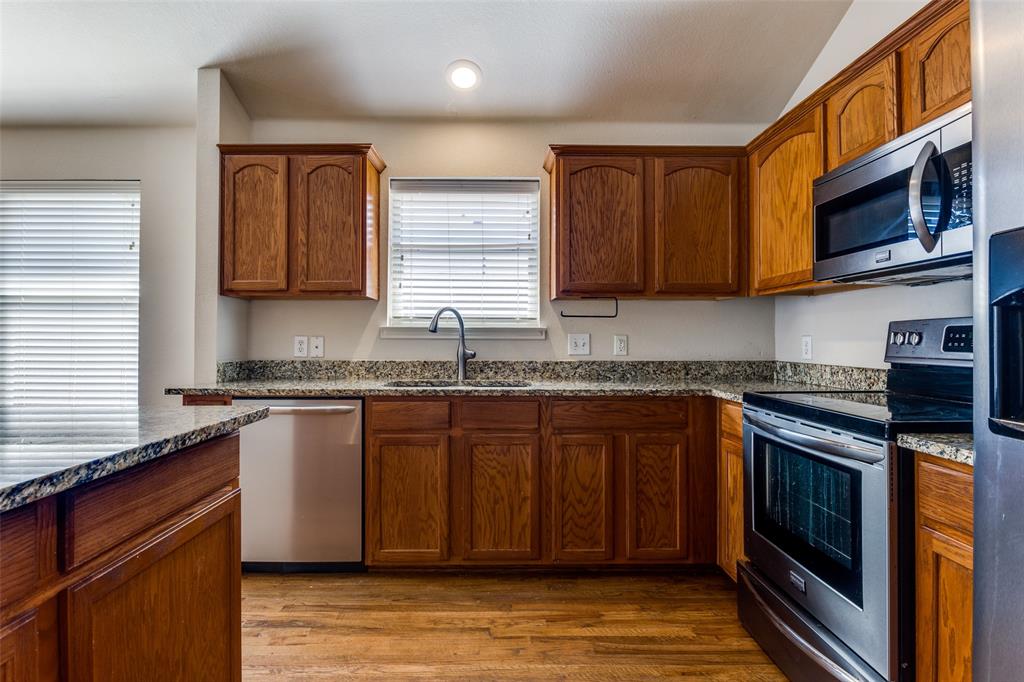 9710 Revolution Way Frisco, TX 75033 - Photo 11 of 25 a kitchen with stainless steel appliances granite countertop a stove a sink and a microwave
