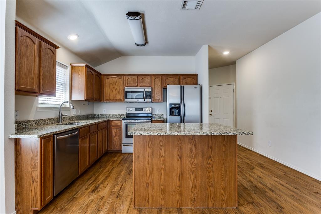 9710 Revolution Way Frisco, TX 75033 - Photo 13 of 25 a large kitchen with stainless steel appliances granite countertop a stove a sink dishwasher and a refrigerator