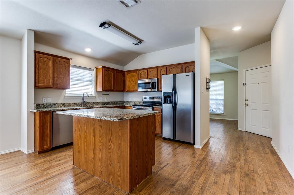 9710 Revolution Way Frisco, TX 75033 - Photo 14 of 25 a kitchen with stainless steel appliances granite countertop a refrigerator a sink dishwasher a stove with wooden floors and granite countertops