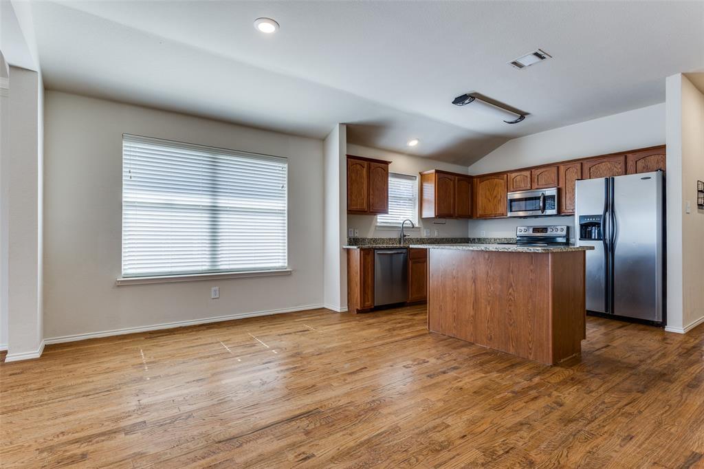 9710 Revolution Way Frisco, TX 75033 - Photo 15 of 25 a kitchen with stainless steel appliances granite countertop a refrigerator a stove top oven a sink and dishwasher with wooden floor