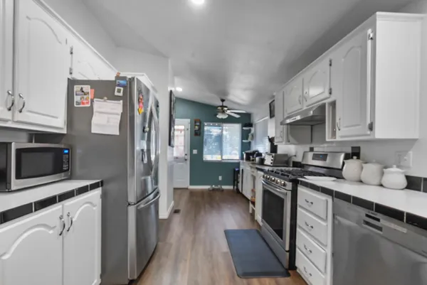 a open kitchen with stainless steel appliances granite countertop a stove top oven a dining table and chairs with wooden floor