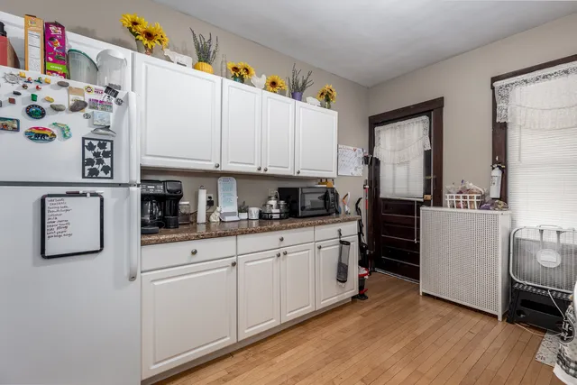 a kitchen with granite countertop a white refrigerator a sink a stove and white cabinets