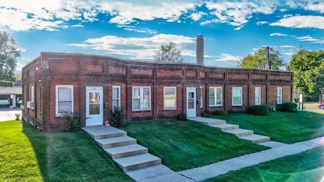 a view of a brick house next to a yard with big trees
