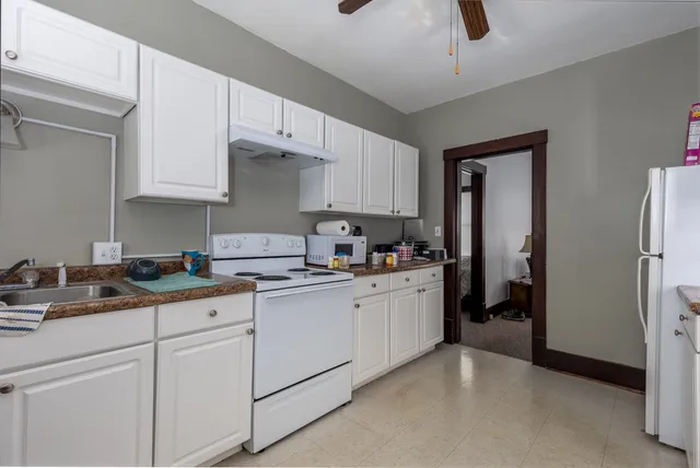 a kitchen with granite countertop white cabinets and white appliances