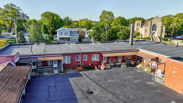 a front view of a building with lots of trees and plants