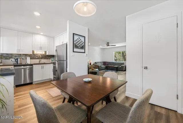 a living room with stainless steel appliances furniture a dining table and kitchen view