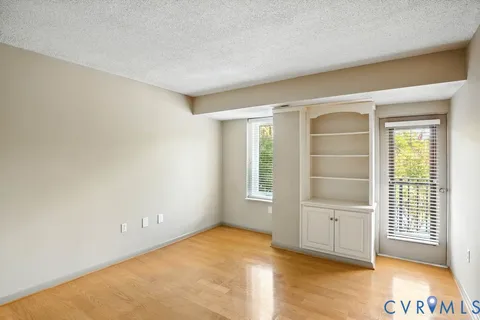 a view of empty room with wooden floor and fan