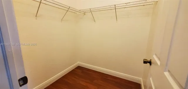 an empty room with wooden floor chandelier fan and windows