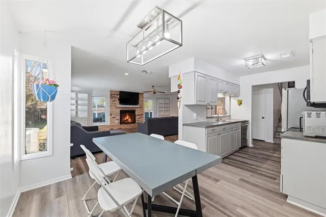 a kitchen with stainless steel appliances granite countertop a stove top oven a sink a refrigerator white cabinets and wooden floor