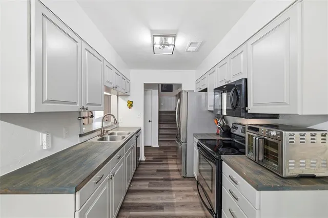 a kitchen with stainless steel appliances granite countertop a stove a refrigerator a sink a dining table and chairs with wooden floor