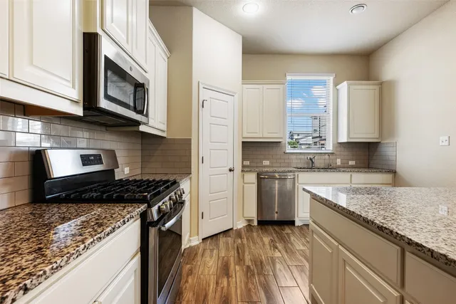 a kitchen with stainless steel appliances granite countertop a stove a sink and a microwave