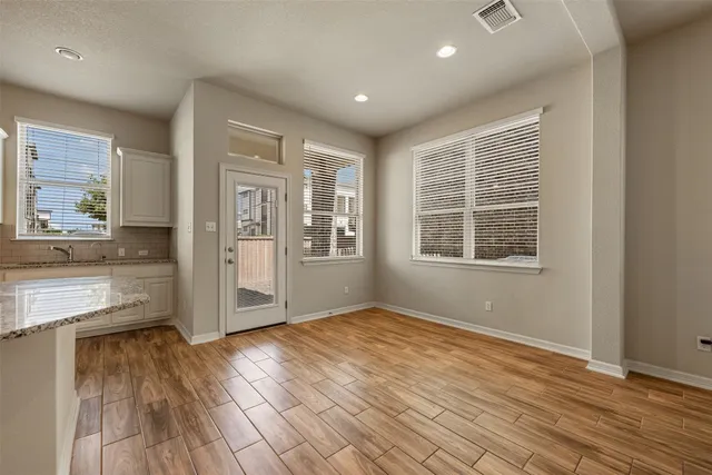 an empty room with wooden floor and windows