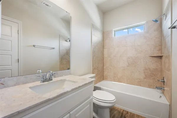 a bathroom with a granite countertop sink a toilet a mirror and bathtub