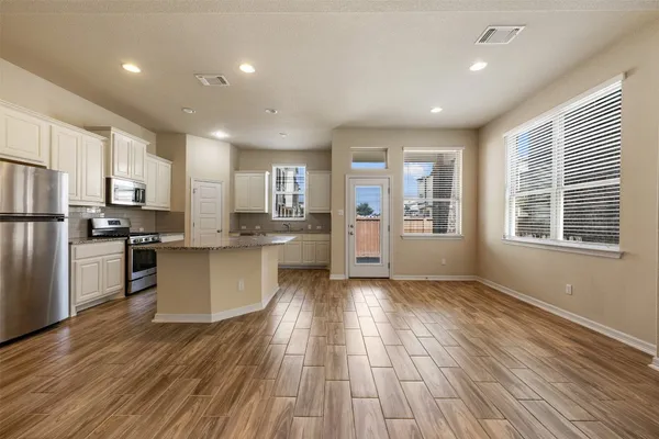 a kitchen with stainless steel appliances kitchen island wooden floors wooden cabinets and entryway