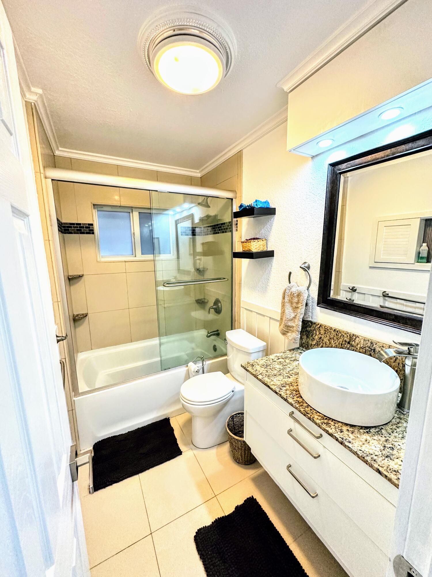 469 Northeast 30th Street Boca Raton, FL 33431 - Photo 15 of 24 a bathroom with a granite countertop toilet sink and mirror