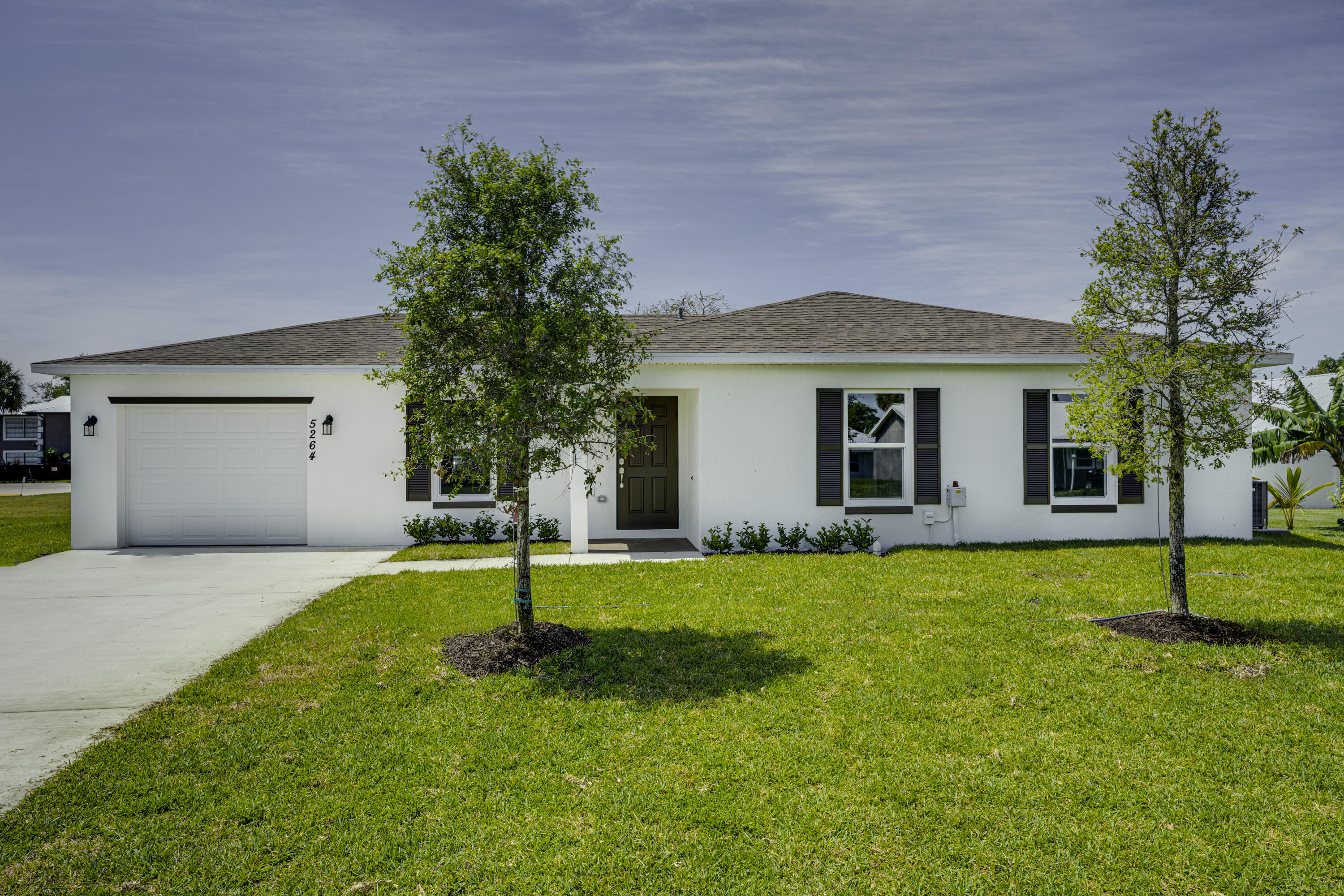 5264 Southeast 43rd Street Okeechobee, FL 34974 - Photo 16 of 16 a white house with a yard and plants