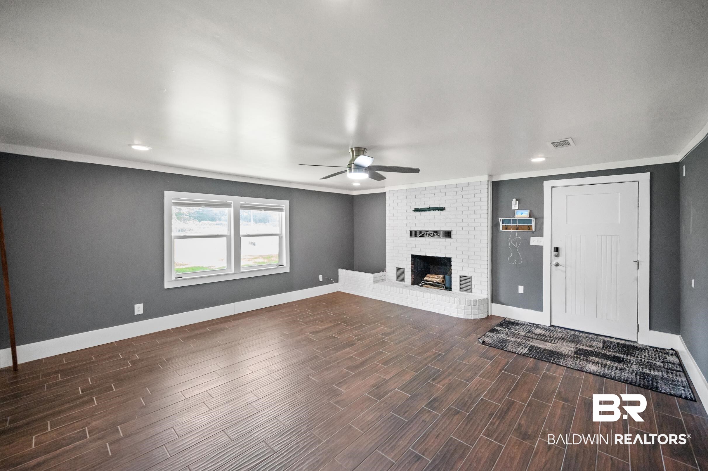 24663 Chestnut Street Elberta, AL 36530 - Photo 4 of 22 Spacious room featuring wood-finish tile flooring and a white brick fireplace with mantel