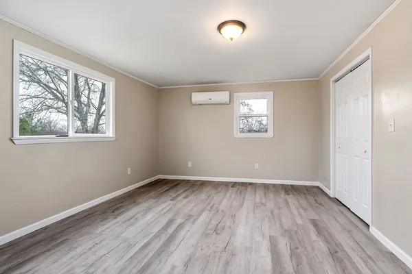 an empty room with wooden floor and windows