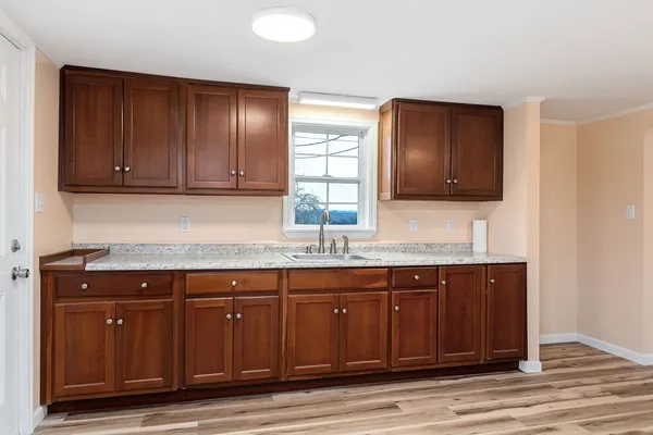 a sink with granite countertop wooden cabinets