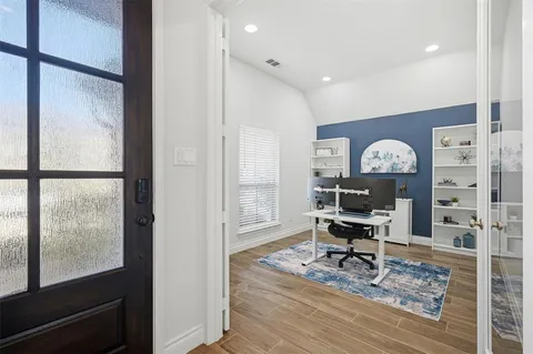 a view of a workspace with wooden floor and a window
