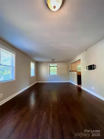 a view of an empty room with window and wooden floor