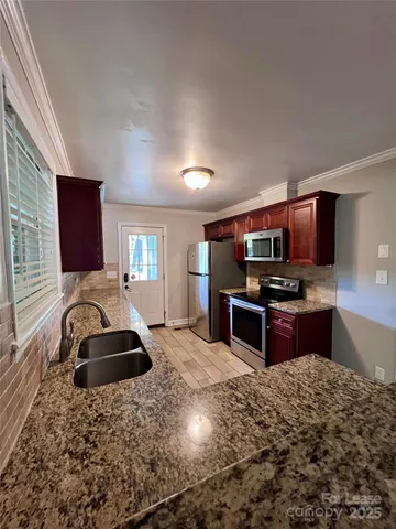 a kitchen with stainless steel appliances kitchen island granite countertop a sink stove and cabinets